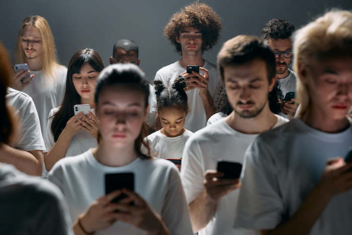 Multiple worshippers in white shirts looking at cellphones