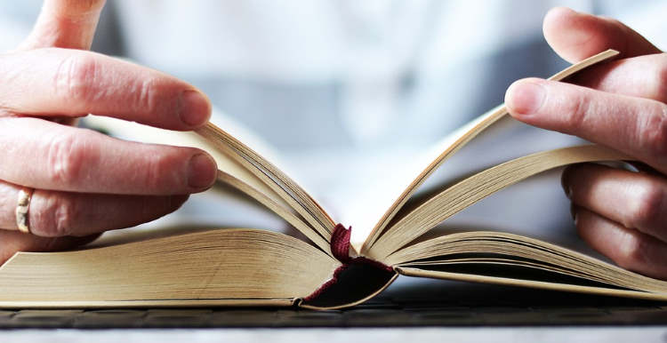 Male hands holding open different parts of a bible