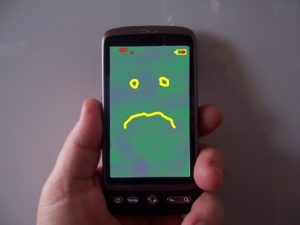 Phone with unhappy face on screen