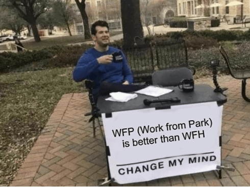 male sitting at folding table and working from park