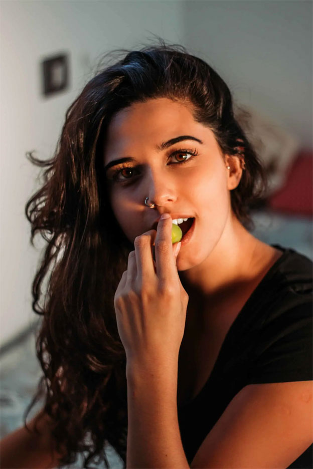 Motivated to improve her diet, a woman eats a healthy fruit.