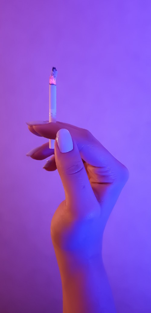 Female hand holding glowing cigarette