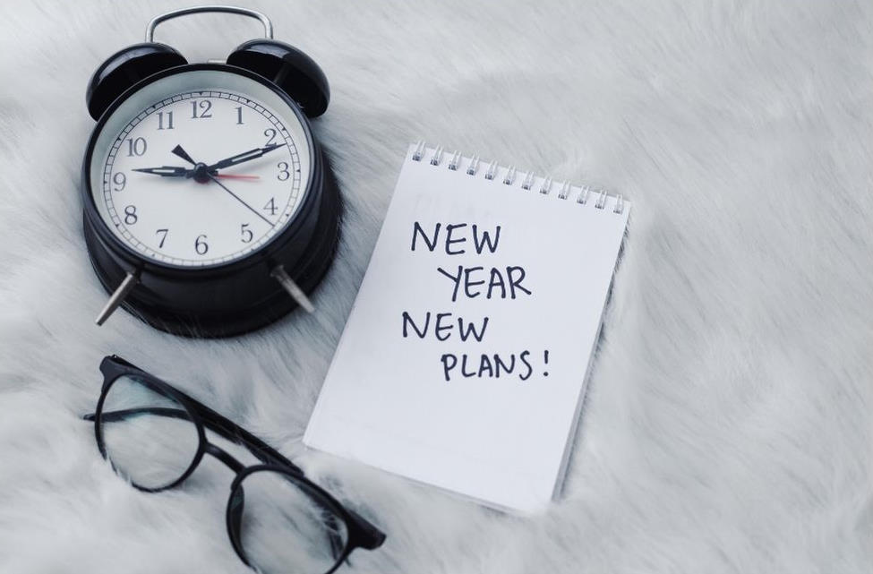 Clock with notepad and message to write new year resolutions.