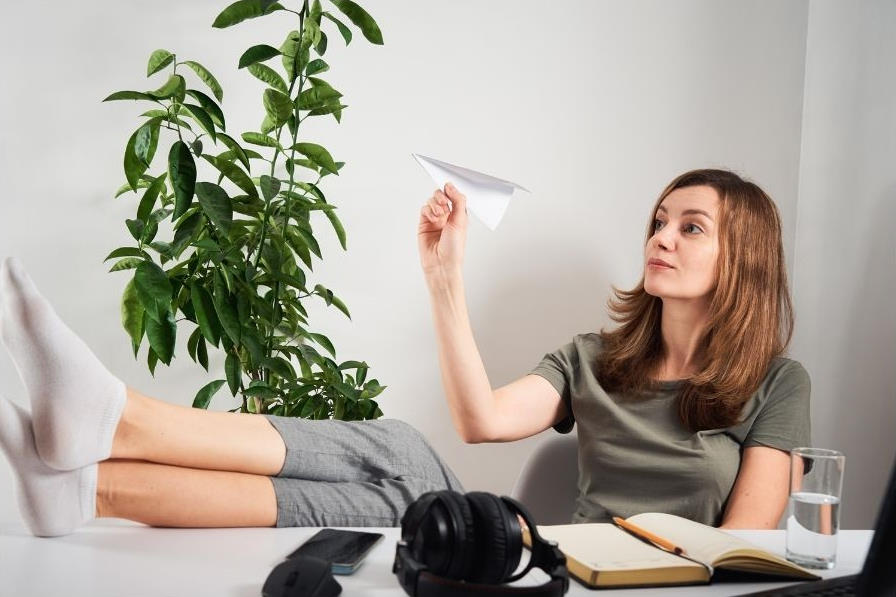 Woman playing with paper airplane instead of studying.